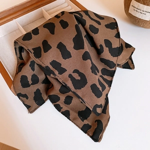 Gros plan d'un foulard en soie léopard drapé sur une boîte à bijoux en bois naturel