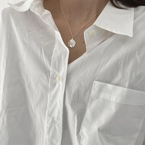 Close-up of 925 sterling silver coin necklace on model wearing white shirt