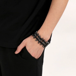 Detail of vintage skull and tiger head motifs on a wide black leather punk bracelet