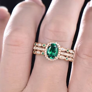 Detailed macro view of three-piece rose gold ring set with emerald-cut green gemstone