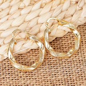 Detailansicht goldener Creolen mit gedrehtem Design und polierter sowie sandgestrahlter Optik