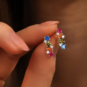 Macro shot of silver drop earrings with vibrant multi-color gemstones held by hand