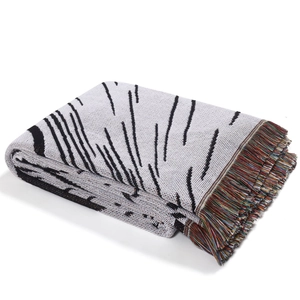 Macro detail of woven throw blanket with black abstract lines and colorful tassels