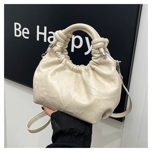 Detail of creamy white pleated cloud bag with knotted handle and fine metal chain strap