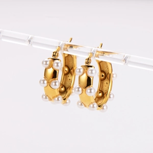 Vintage 18k gold U-shaped hollow earrings with white pearls on a minimalist display