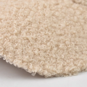 Close-up of beige faux shearling fabric texture on embroidered C letter baseball cap