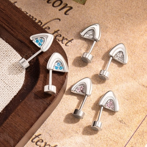 Silver kitten ear cartilage studs with blue, white, and pink zircon stones on wood