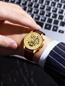 Detail view of WOKAI men's gold skeleton watch with brown leather strap on wrist