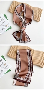 Detail of a brown silk-like scarf with white chain patterns on wooden decorative board