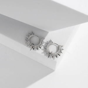 Macro shot of silver spike hoop earrings with micro-inlaid zircon on white pedestal