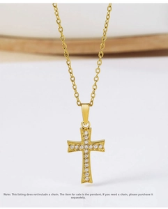 Macro detail of gold-plated cross pendant with white zircon stones on white background