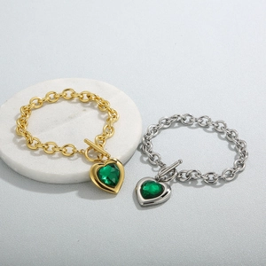 Detail of heart-shaped green crystal pendants on chunky stainless steel toggle bracelets
