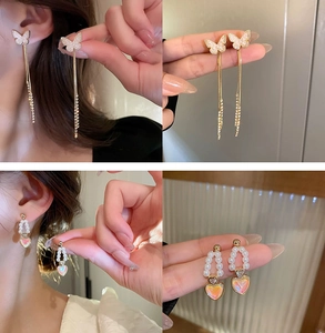 Detail of gold butterfly tassel earring and pearl heart charm with iridescent pendant
