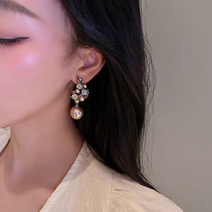 Close-up of vintage flower earrings with colorful crystals and hanging pearl on a model