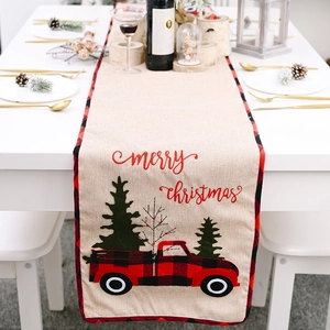 Christmas table runner with red truck and plaid border on a festive dining set