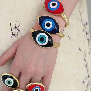 Close-up of vibrant evil eye enamel bangles and rings with a vintage gold finish