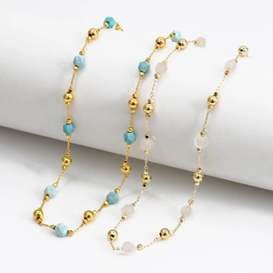 Detail of bohemian gold chains with turquoise and pink stones on a white stand