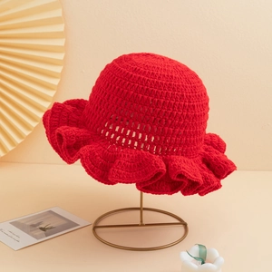 Close-up of red crochet knit fisherman hat with ruffle brim on a gold metal stand