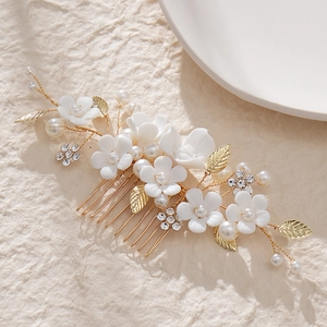 Detail shot of ceramic white flowers and pearls on golden bridal hair comb pins