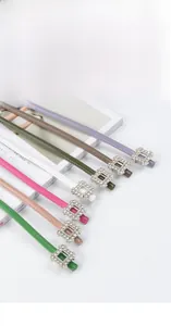 Close-up of thin leather belts with sparkling rhinestone square buckles in multiple colors