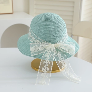 Detail of mint green straw sun hat with delicate white lace floral embroidery bow