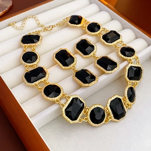 Detail of vintage gold-framed black crystal necklace and earrings set in a white box