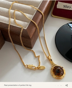 Detailed close-up of a gold necklace with a brown crystal pendant and lobster clasp