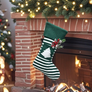Gros plan d'une chaussette de Noël tricotée à rayures vertes avec applique sur cheminée