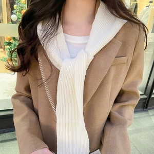 Detail of camel wool coat paired with white ribbed knit scarf hood for winter warmth