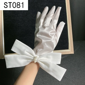 Detail of white satin bridal gloves featuring a large bow and pearl accents