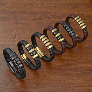 Mens woven leather bracelets with gold and black magnetic clasps on dark wood background