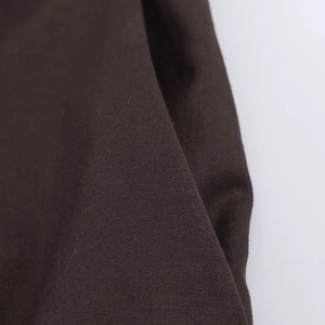 Détail macro du tissu tissé marron foncé montrant la texture fine du blazer chic
