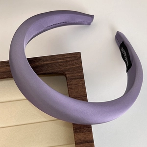 Detail of purple satin padded headband with hand made label on a wooden frame