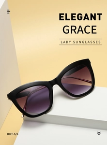 Close-up of cat-eye sunglasses with black frame and purple gradient lenses on stand