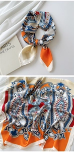 Detailed view of paisley silk scarf in orange and navy blue showing satin texture