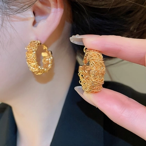 Detail of gold-plated woven metal wire hoop earrings with unique bird nest texture