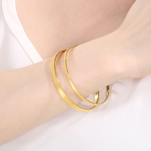 Close-up of dual stackable polished 18k gold-plated stainless steel bangles on wrist