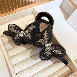Close-up of black mesh butterfly hair clip with gold embroidery and white pearls