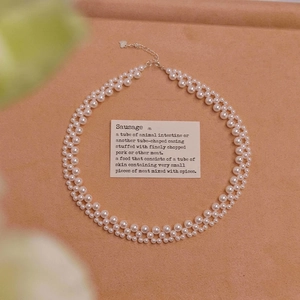 Detail of double-layer woven pearl necklace with silver heart pendant and lobster clasp