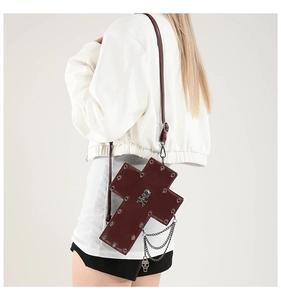 Detail of burgundy gothic cross bag with metal rivets, skull head, and chain tassels