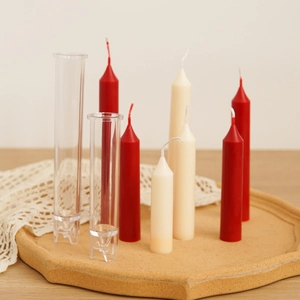Clear acrylic cylinder candle molds with finished red and beige taper candles on tray