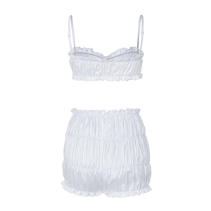 Detail of white satin camisole set featuring ruffled hem and pleated fabric texture