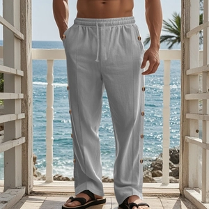 Close-up of gray linen pants featuring drawstring waist and decorative side buttons on beach