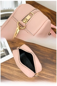 Detail of pink leather crossbody bag showing golden metal zipper and black inner compartment