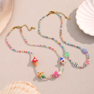 Détail de colliers en perles colorées avec pendentifs champignon, poisson et fermoir en or 18K