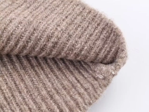 Macro shot of light coffee ribbed knit fabric showing soft wool texture and warm fibers