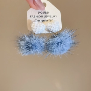 Dettaglio di orecchini con pompon blu e cuore in tweed con perni in argento S925