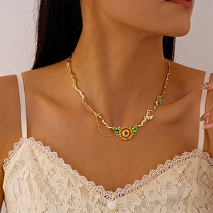 Detail of sunflower and bee pendant on a gold textured chain worn by a female model