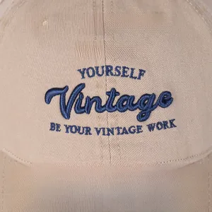 Close-up of premium khaki baseball cap with navy blue vintage letter embroidery detail