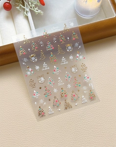 Detailed view of Christmas nail art stickers with gold foil trees and snowflake patterns